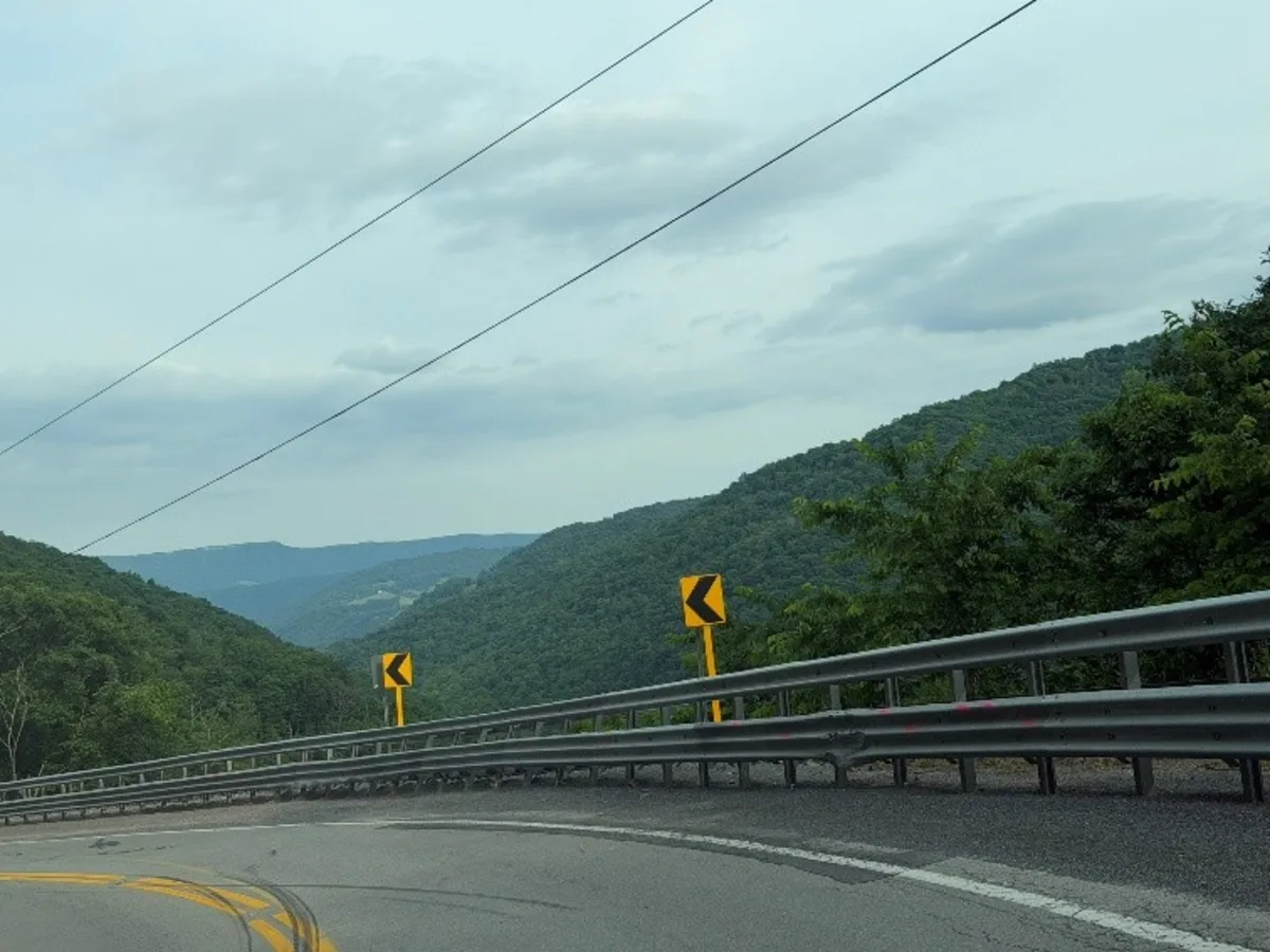Guardian 5 steel guardrail barrier along a sharp curve on a steep West Virginia mountain grade