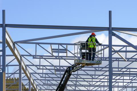 A construction worker is in a boom lift basket in a strut channel background.